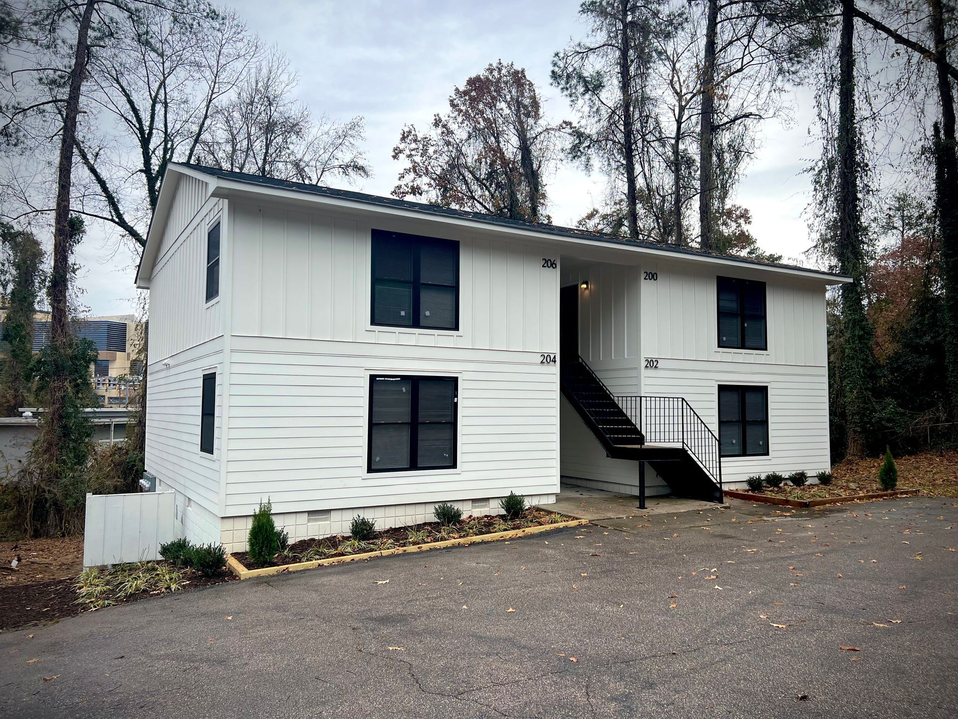 A white house with stairs leading up to it is surrounded by trees.