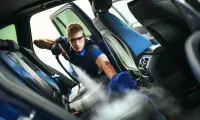 Detailing a car interior with blue microfiber cloth and cleaning tools visible