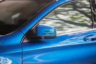 Blue car door and side mirror with trees reflected in the window