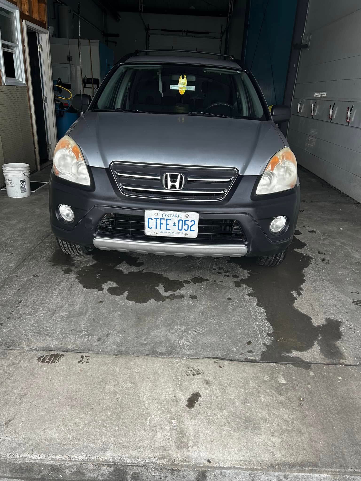 Black Honda SUV parked in a garage, front view with headlights and license plate visible.