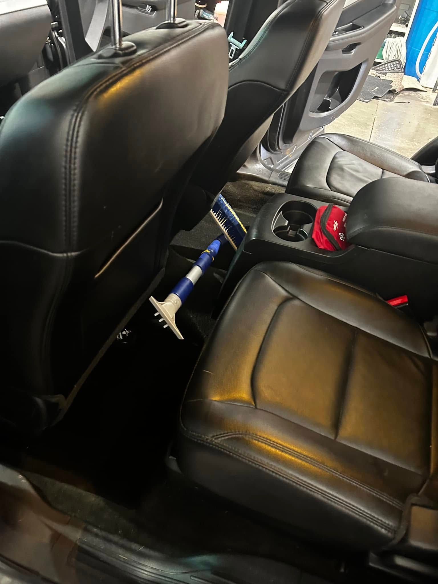 Black car seat interior with a blue-and-white handicap cane resting between the seats
