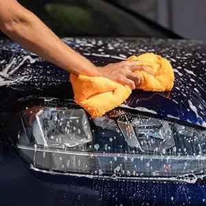 Pressure washing the front of a blue truck with a spray nozzle