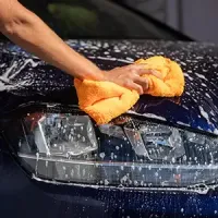 Pressure washing the front of a blue truck with a spray nozzle
