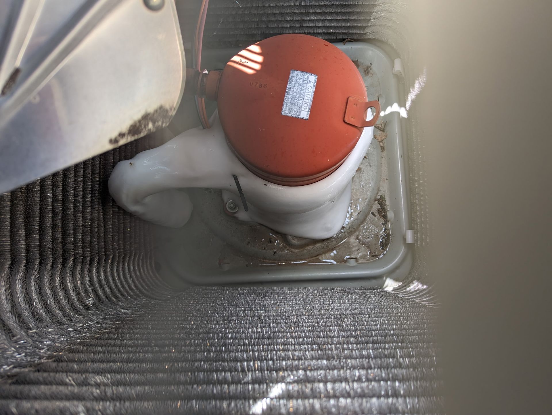 Close-up of an outdoor HVAC unit, showing wet fan motor and condenser coils.
