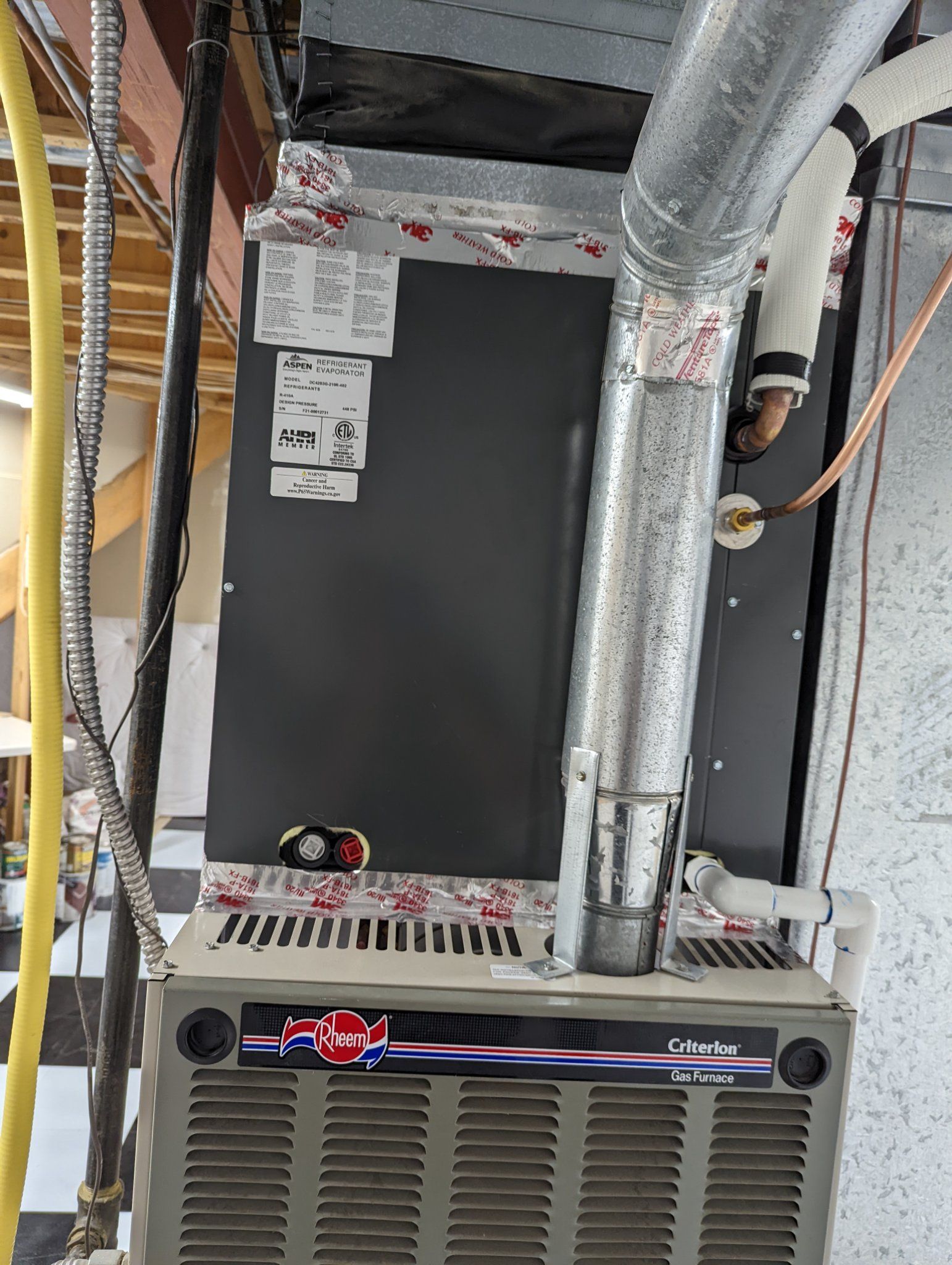 Furnace with silver ductwork and connected piping in a basement setting.