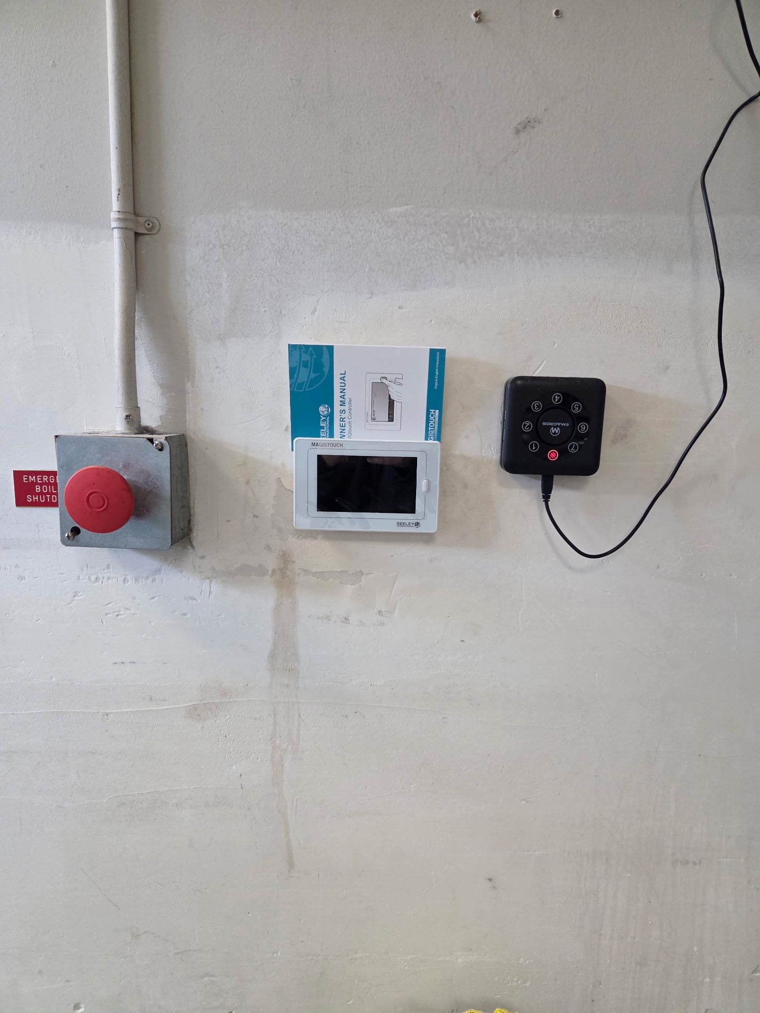 Fire alarm pull station, intercom, and black box with buttons mounted on a white wall.