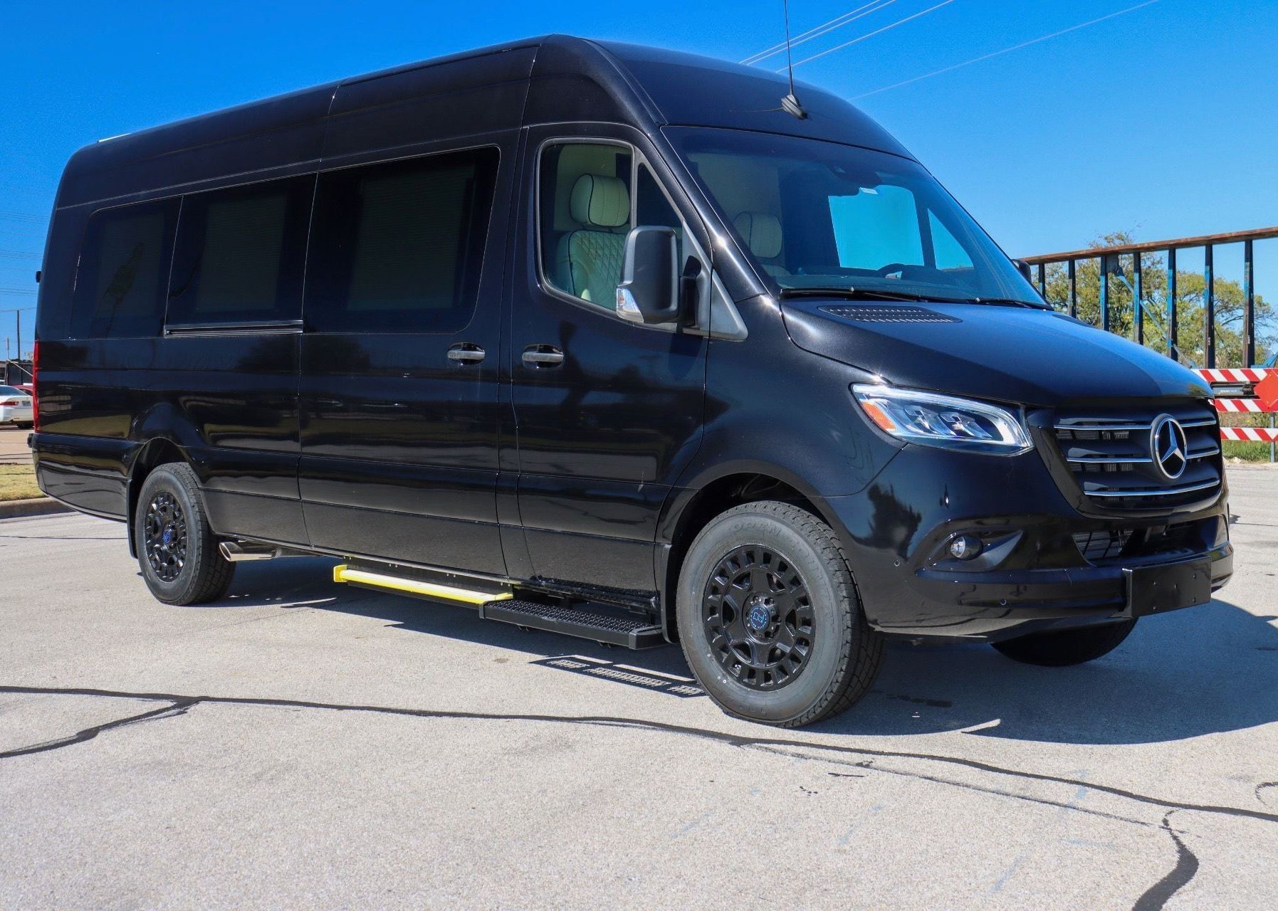 A black mercedes sprinter van is parked in a parking lot.