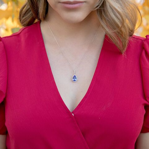 Close-up of a woman in a bright pink dress wearing a blue pendant necklace