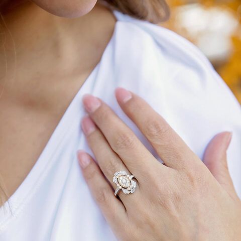 Hand on white dress showing a diamond engagement ring close-up