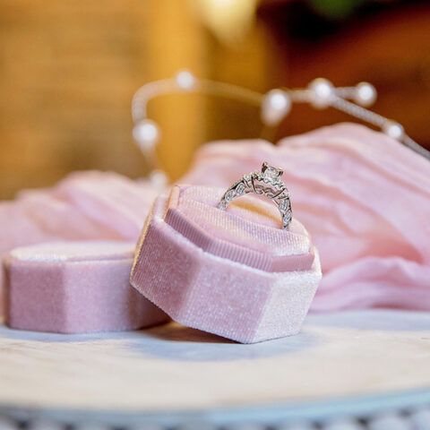 Diamond ring on pink velvet jewelry boxes with a soft pink ribbon backdrop