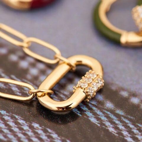 Gold chain links with a jeweled clasp on a textured surface