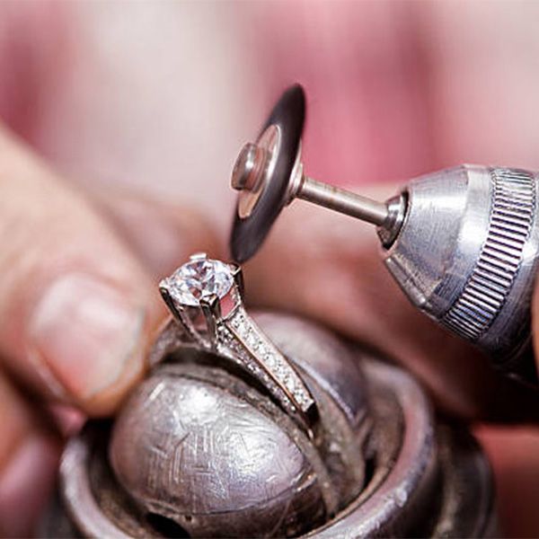 Jewelers polishing a diamond ring with a rotary tool, close-up