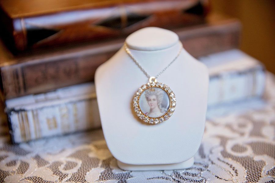 Photo necklace displayed on a white jewelry bust with a lace background
