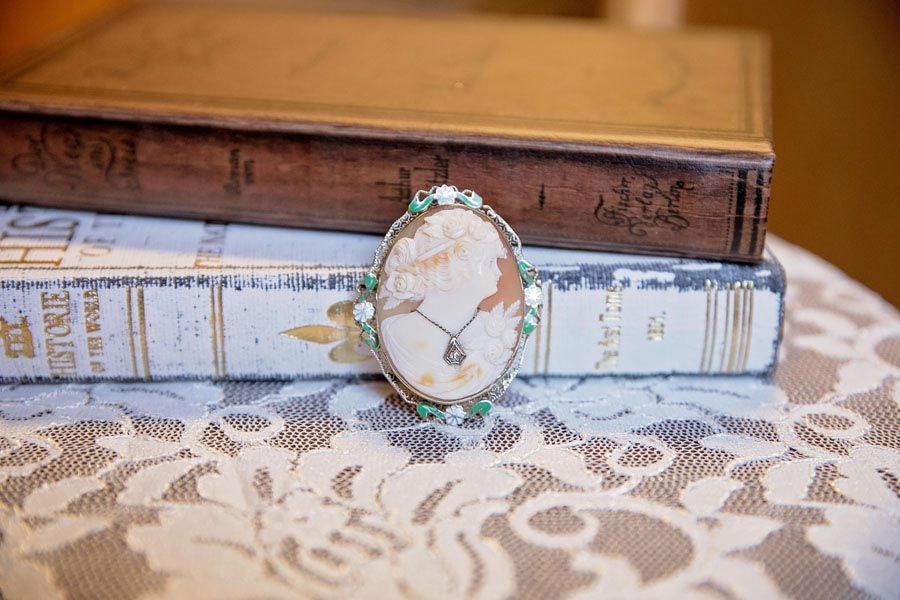 Decorative oval brooch leaning against stacked books on a lace tablecloth