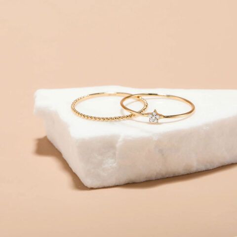 Gold rings on a white stone block against a beige background