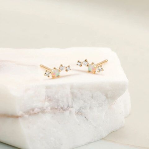 Gold stud earrings with clear stones on a white marble block