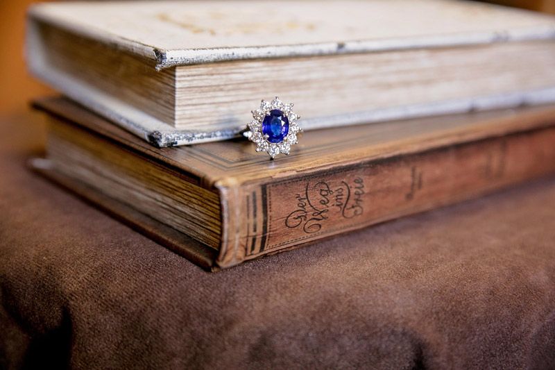 Stacked vintage books with a blue gemstone ring resting on the spine