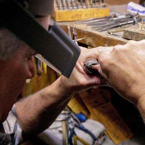Hands using a tool to sharpen a blade at a workbench in a workshop