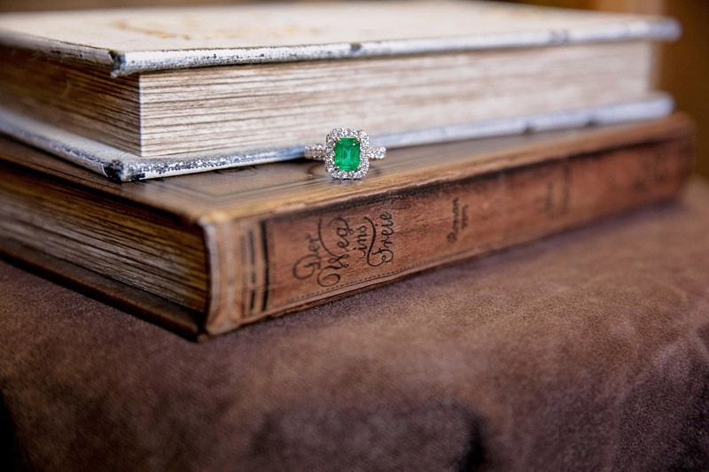Stack of old books with a green gemstone ring resting on the lower spine