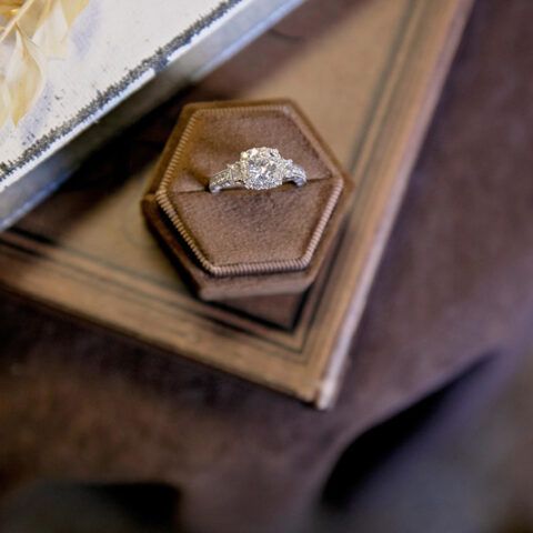 Diamond ring on a brown hexagonal ring box atop an open book