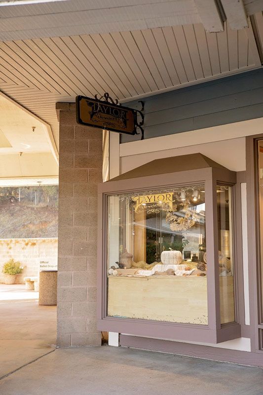 Storefront display window under a covered walkway with a hanging sign and beige trim