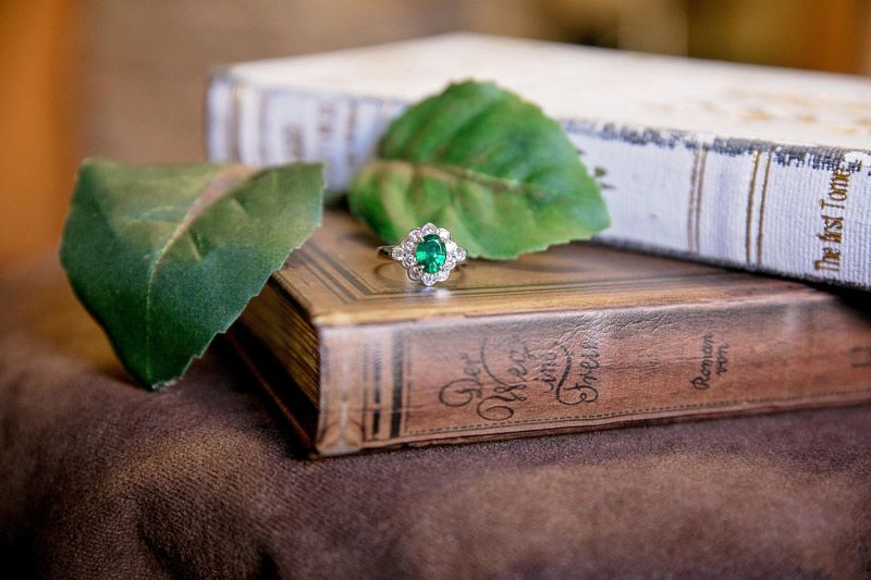 Green ring on stacked vintage books with leaves on a brown surface