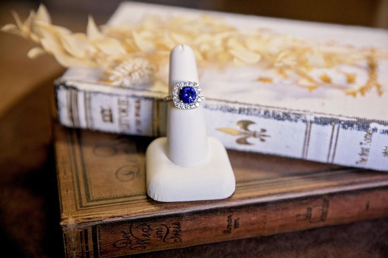 White ring display stand with a blue gemstone ring on stacked vintage books