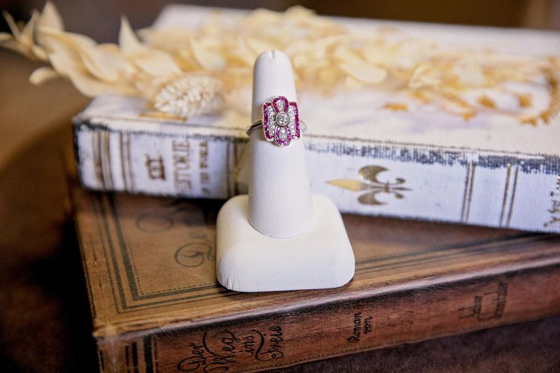 White ring in a stand on stacked vintage books with dried flowers in the background