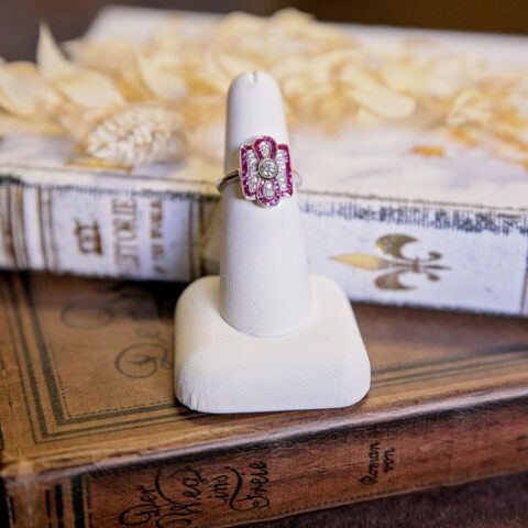 Red gemstone ring on a white display stand atop stacked vintage books