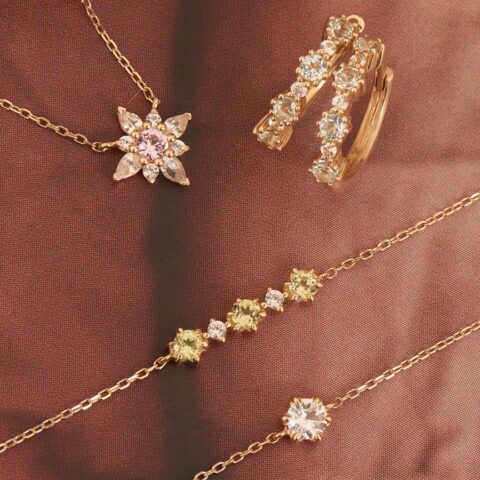 Gold necklaces and a ring with floral and diamond-like gemstone designs on a brown fabric background
