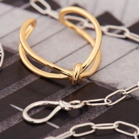 Gold knot bracelet with silver chain links on a gray fabric background