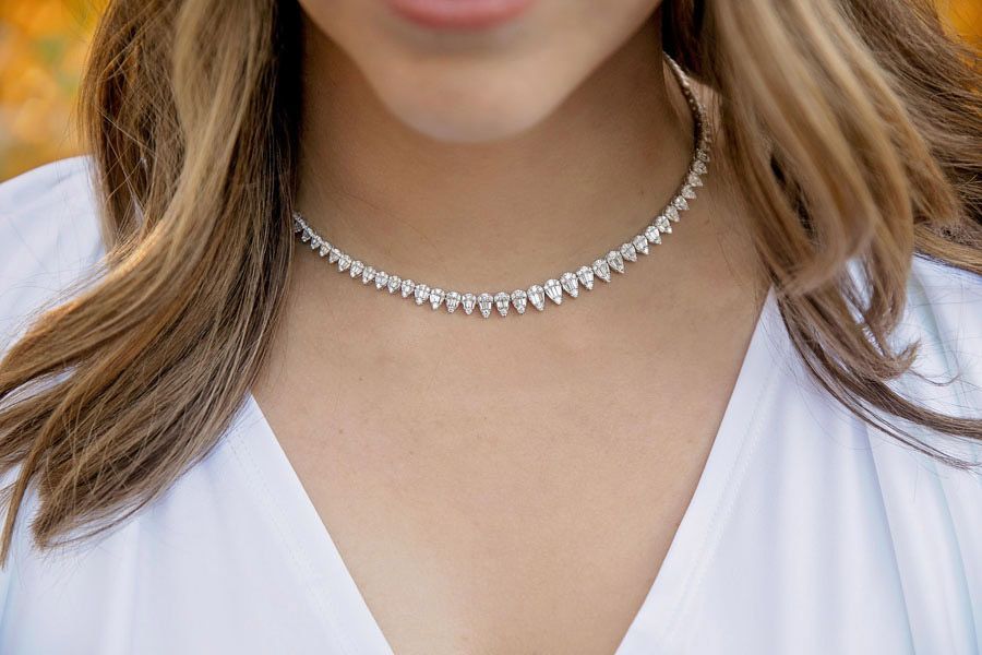 Close-up of a woman wearing a sparkly choker necklace and white top