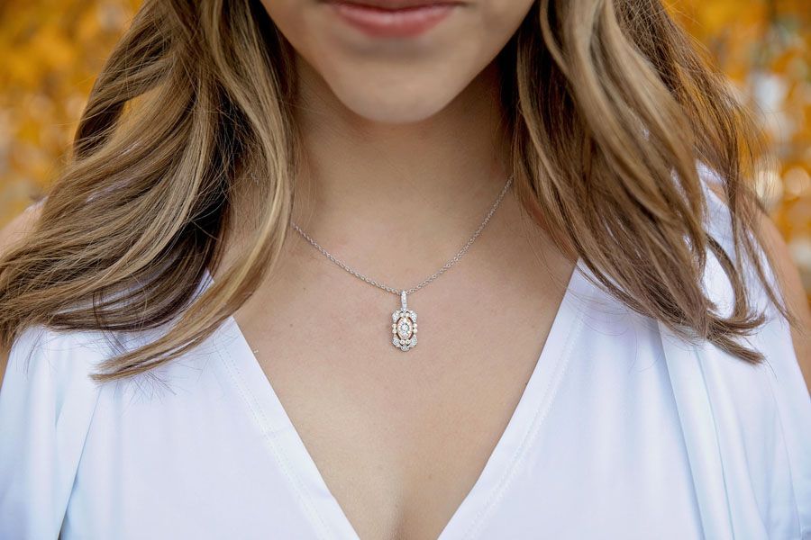 Woman in white V-neck top wearing a silver pendant necklace