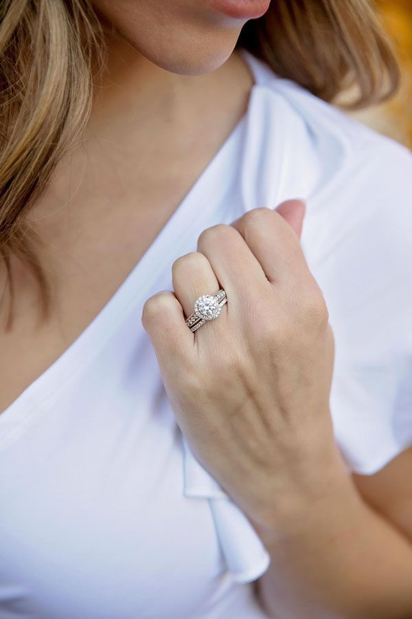 Woman in white top holding a ringed hand near her chest