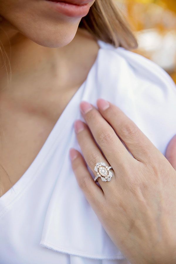 Hand resting on white blouse, showing a diamond ring.
