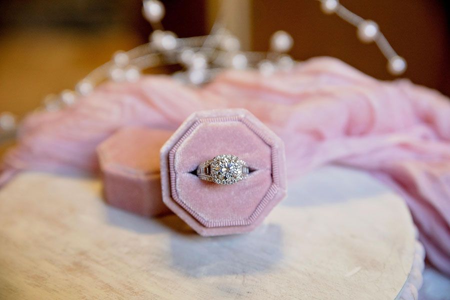 Pink octagonal velvet ring box with a silver diamond ring on a soft surface