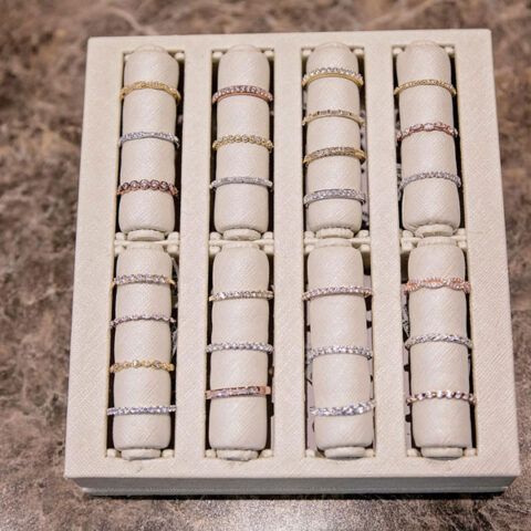 A jewelry box with four rows of stacked rings in white and gold tones.