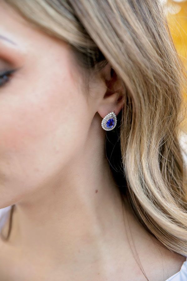 Close-up of a woman’s ear wearing a blue teardrop earring with a silver border