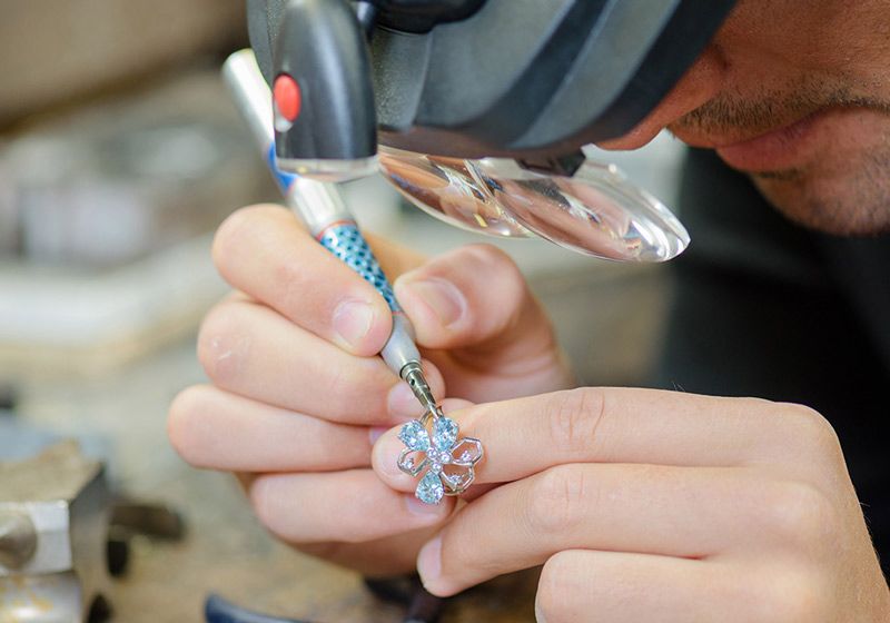 Hands use pliers to adjust a blue-and-silver beaded earring.