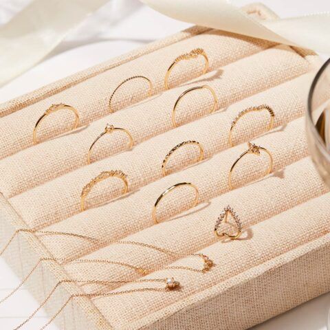 Gold delicate rings arranged in a beige velvet jewelry display tray