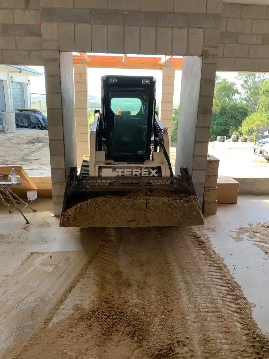 A Terex Skid Steer Loader Moving Dirt Through an Open Doorway in A Building Under Construction — Bailey's Bobcat & Excavator Hire In Dumbleton, QLD