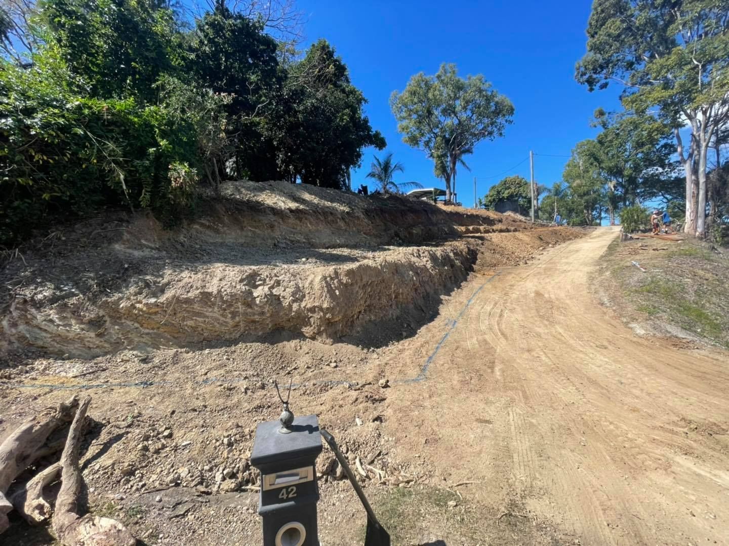 Dirt Path Leading Uphill, Trees, and Terraced Earth Under a Blue Sky — Bailey's Bobcat & Excavator Hire In Dumbleton, QLD