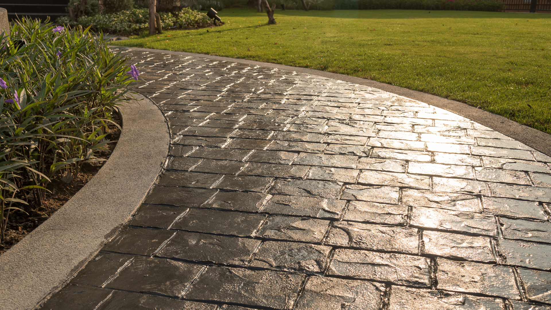 A brick walkway leading to a lush green field.