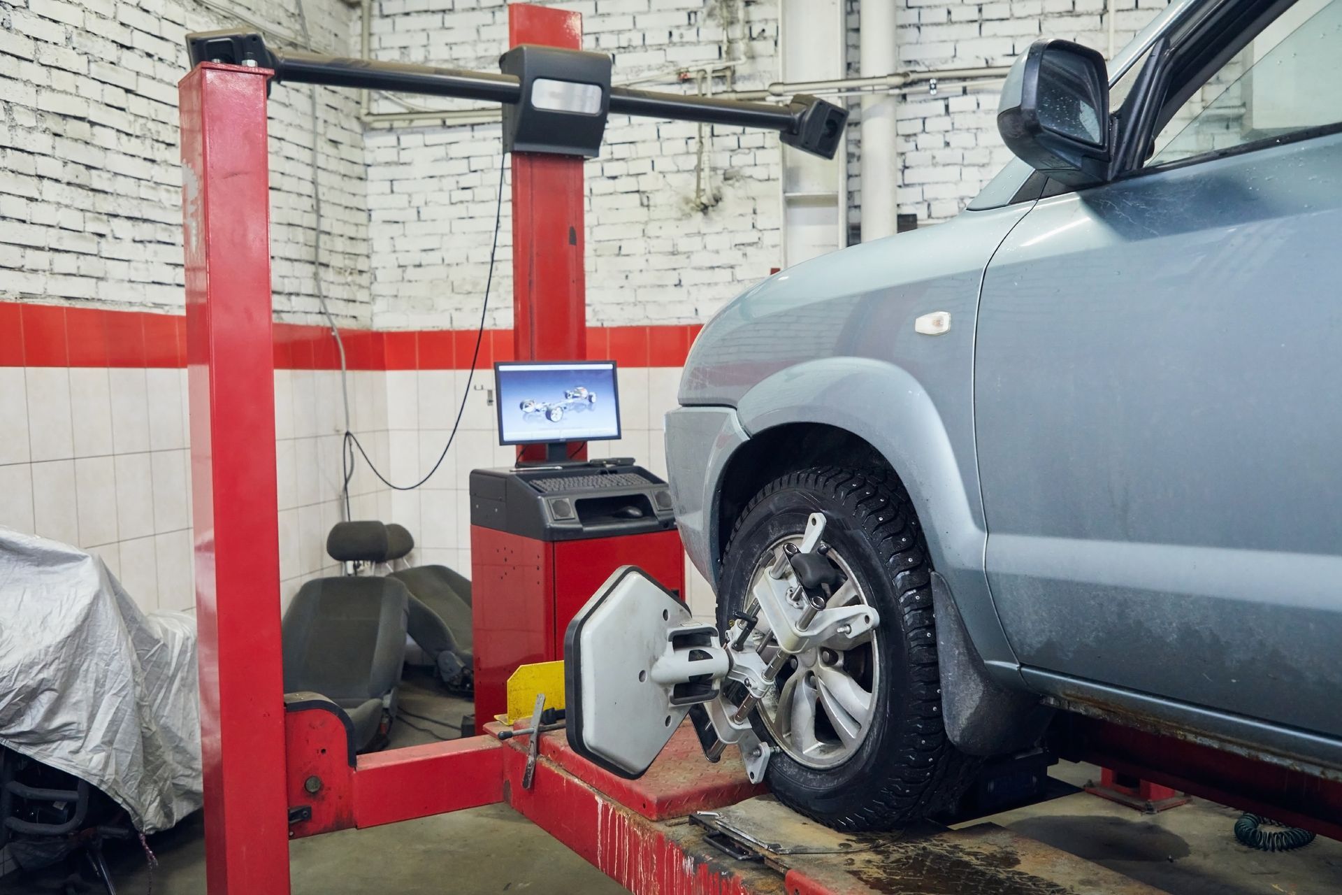 SUV on a tire balancing machine in an auto repair shop with red equipment and white brick walls SUV on a tire balancing machine in an auto repair shop with red equipment and white brick walls