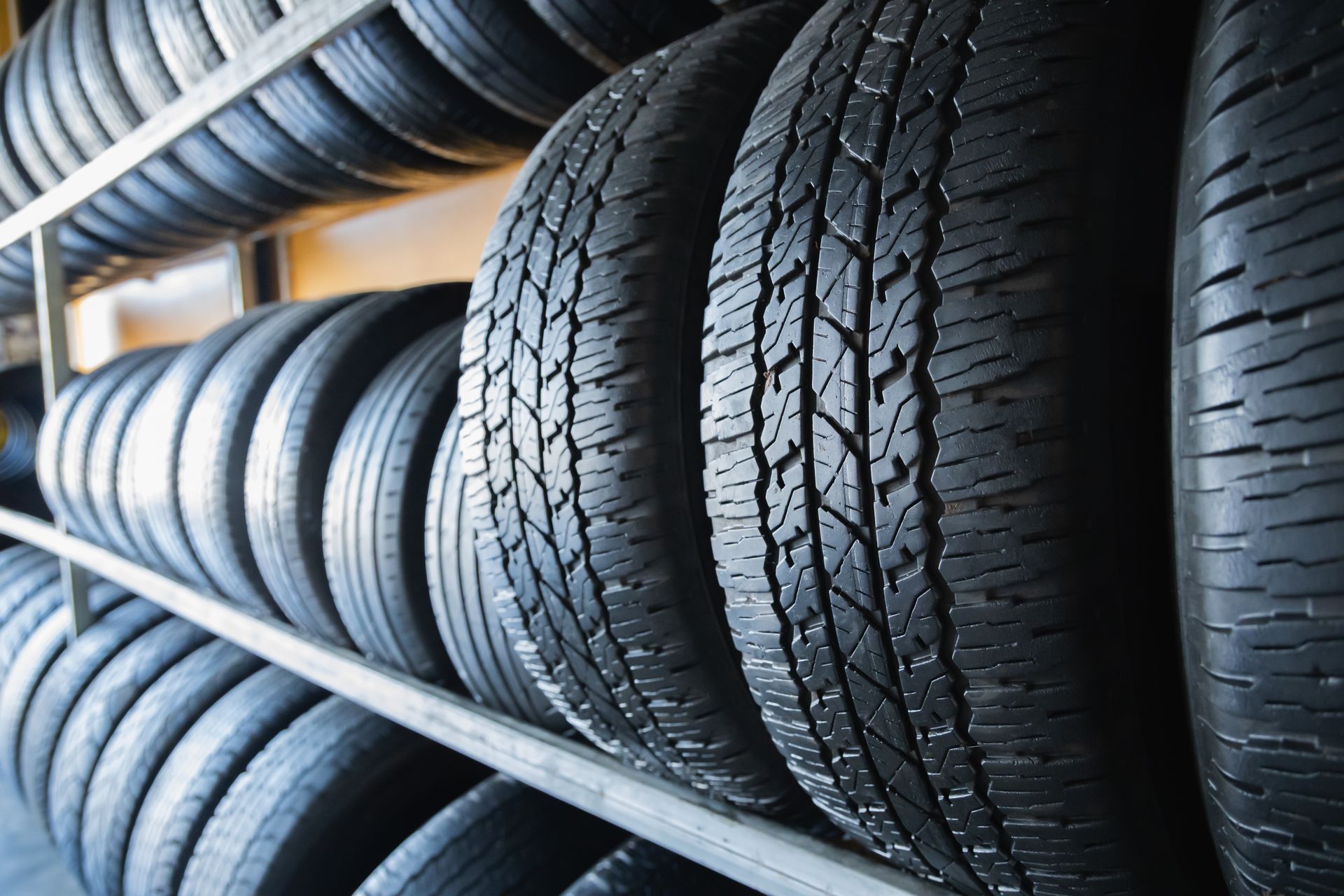 Rows of black tires stacked on metal shelves in a warehouse. Rows of black tires stacked on metal shelves in a warehouse.