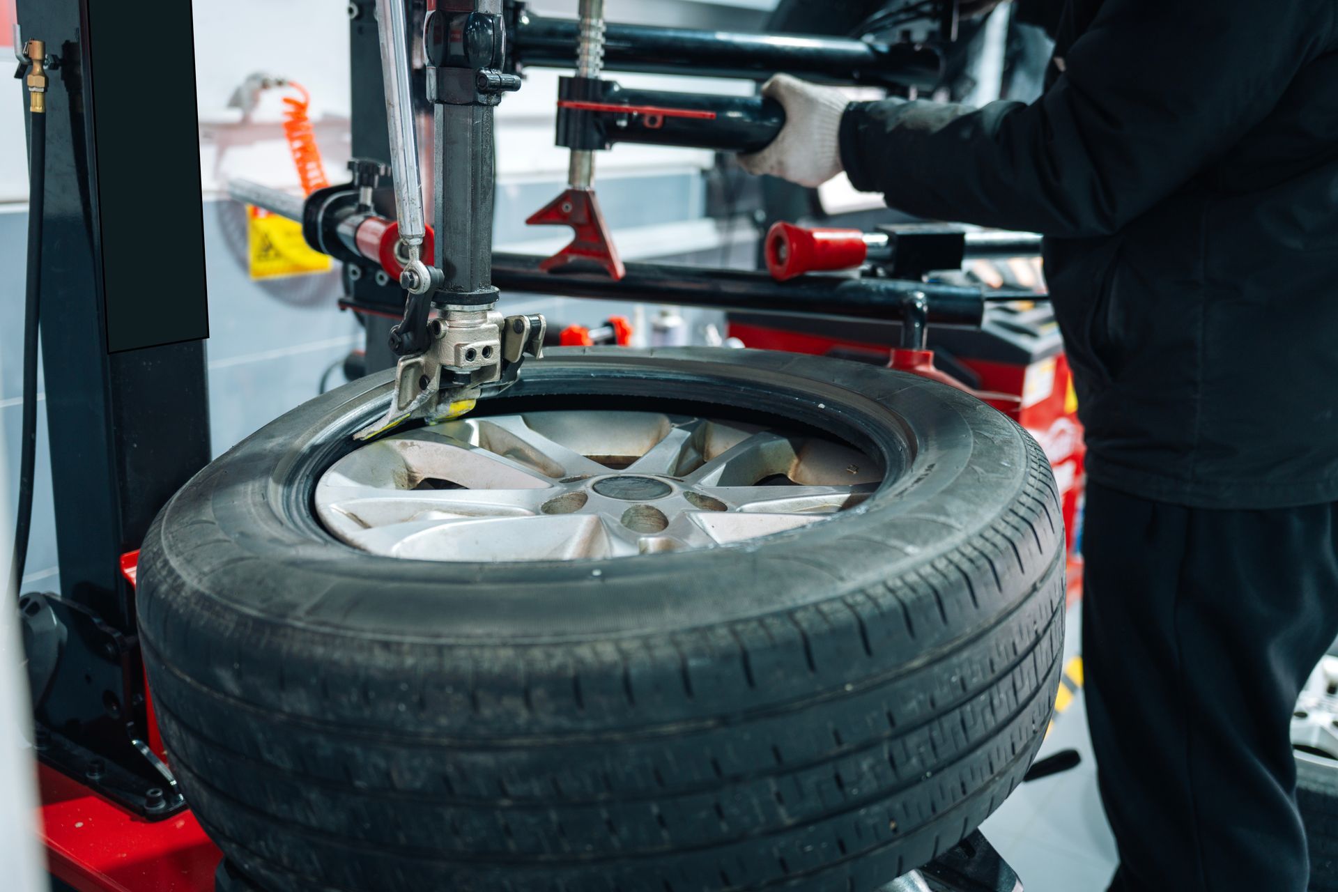 Worker changing a car tire with a tire machine in a garage Worker changing a car tire with a tire machine in a garage