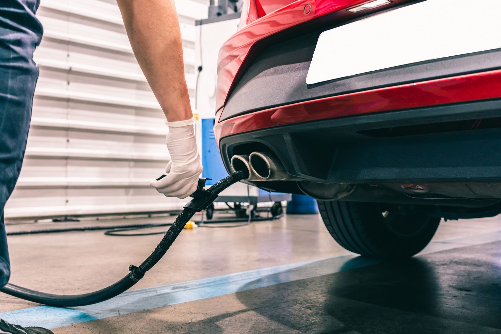 Person vacuuming the floor beside a red car in a garage Person vacuuming the floor beside a red car in a garage
