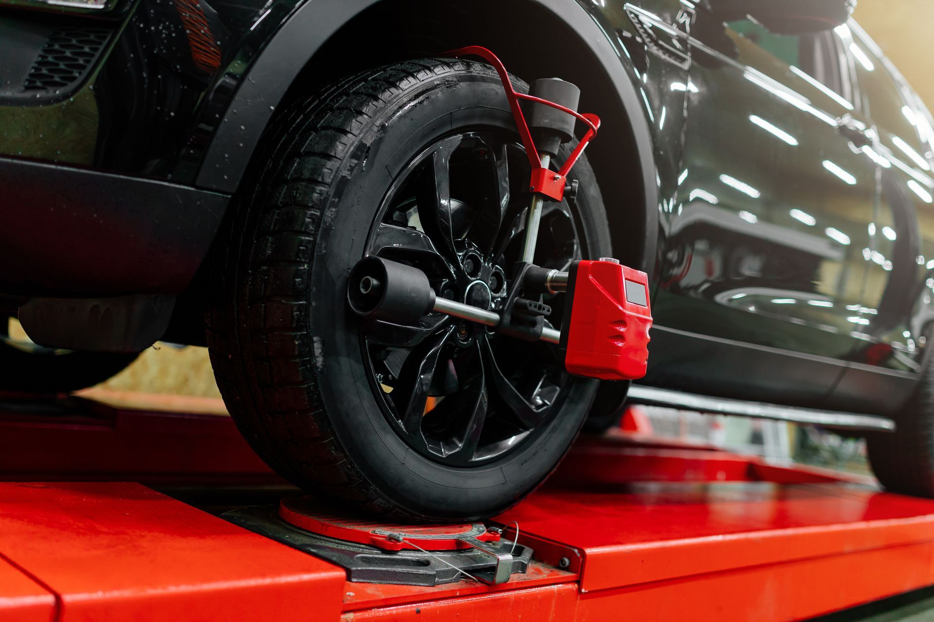 Black car wheel with a red tire clamp on a red platform in a garage or workshop Black car wheel with a red tire clamp on a red platform in a garage or workshop