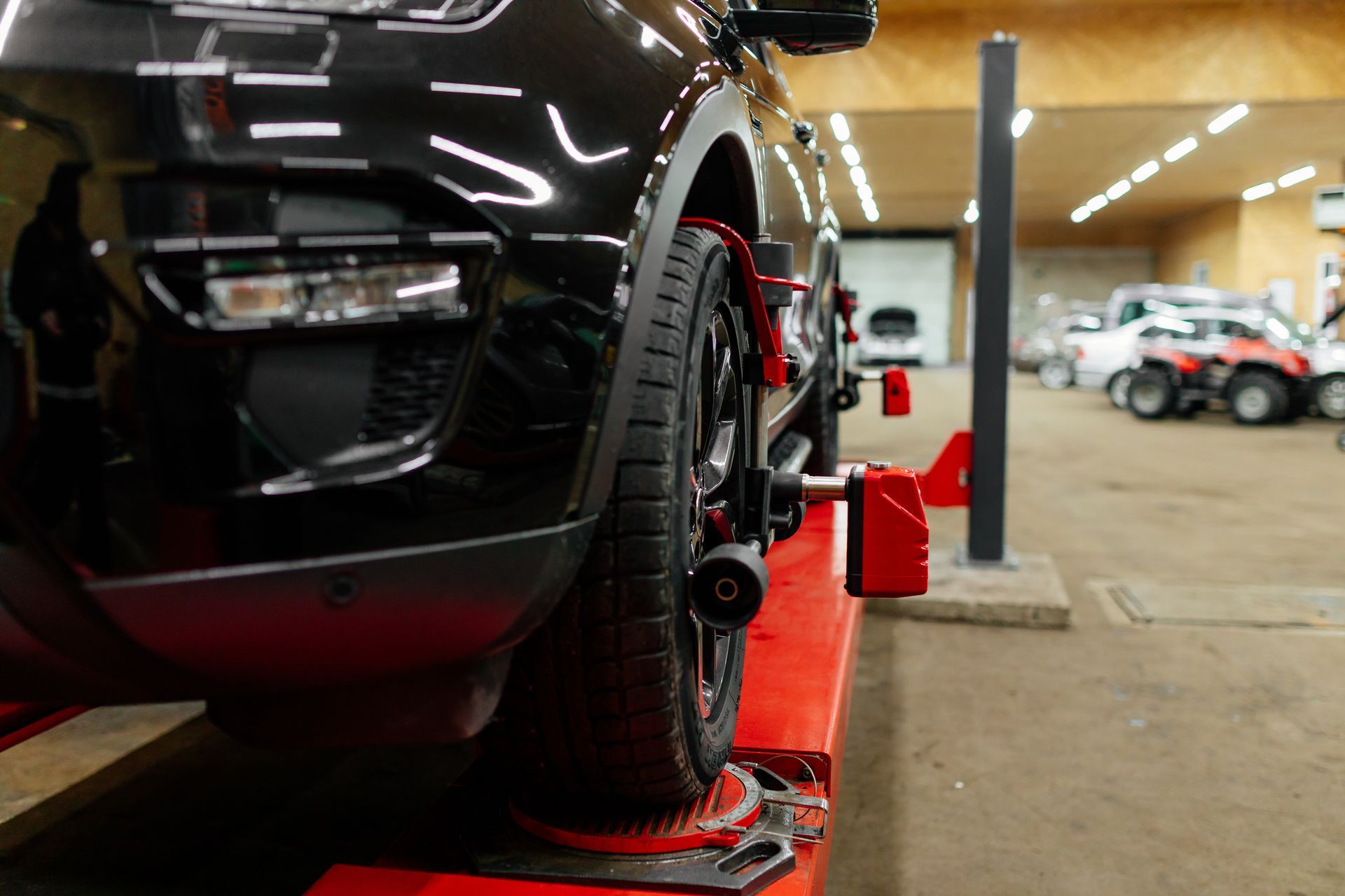 Black car on a red lift in an auto shop, front wheel aligned for maintenance Black car on a red lift in an auto shop, front wheel aligned for maintenance
