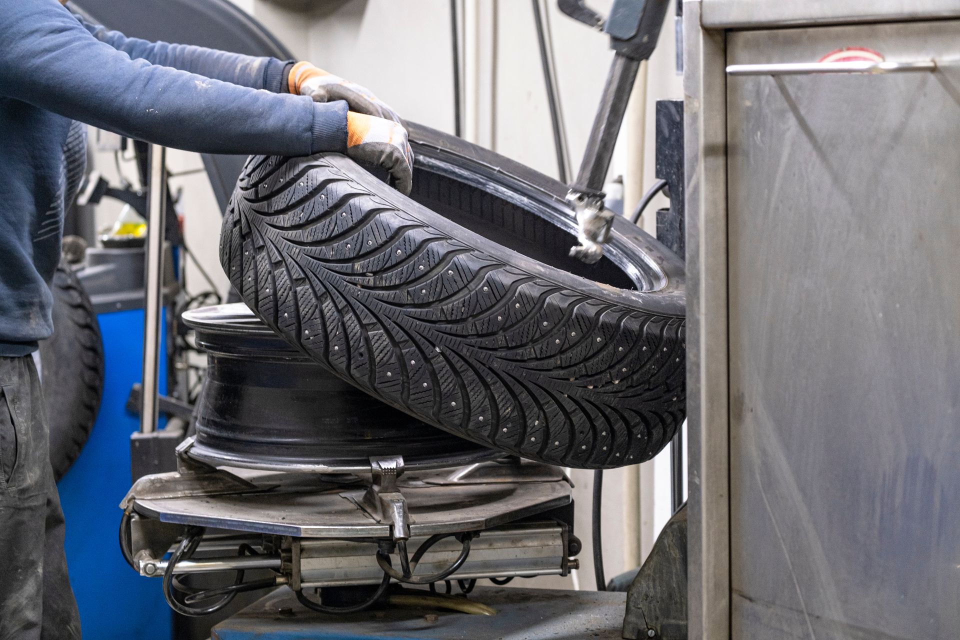 Mechanic lifting a car tire onto a wheel balancing machine in an auto shop. Mechanic lifting a car tire onto a wheel balancing machine in an auto shop.
